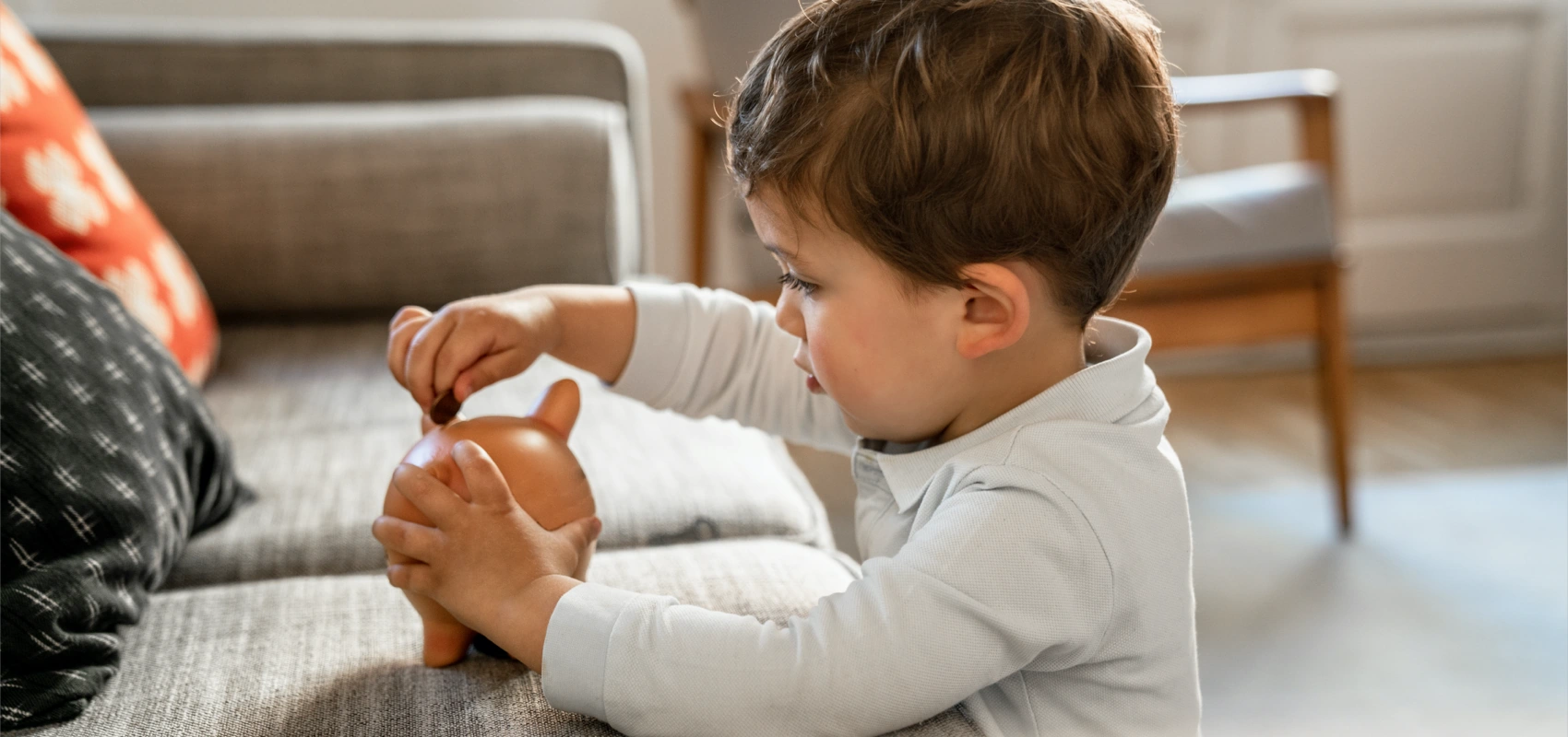 Boy placing coins into a piggy bank