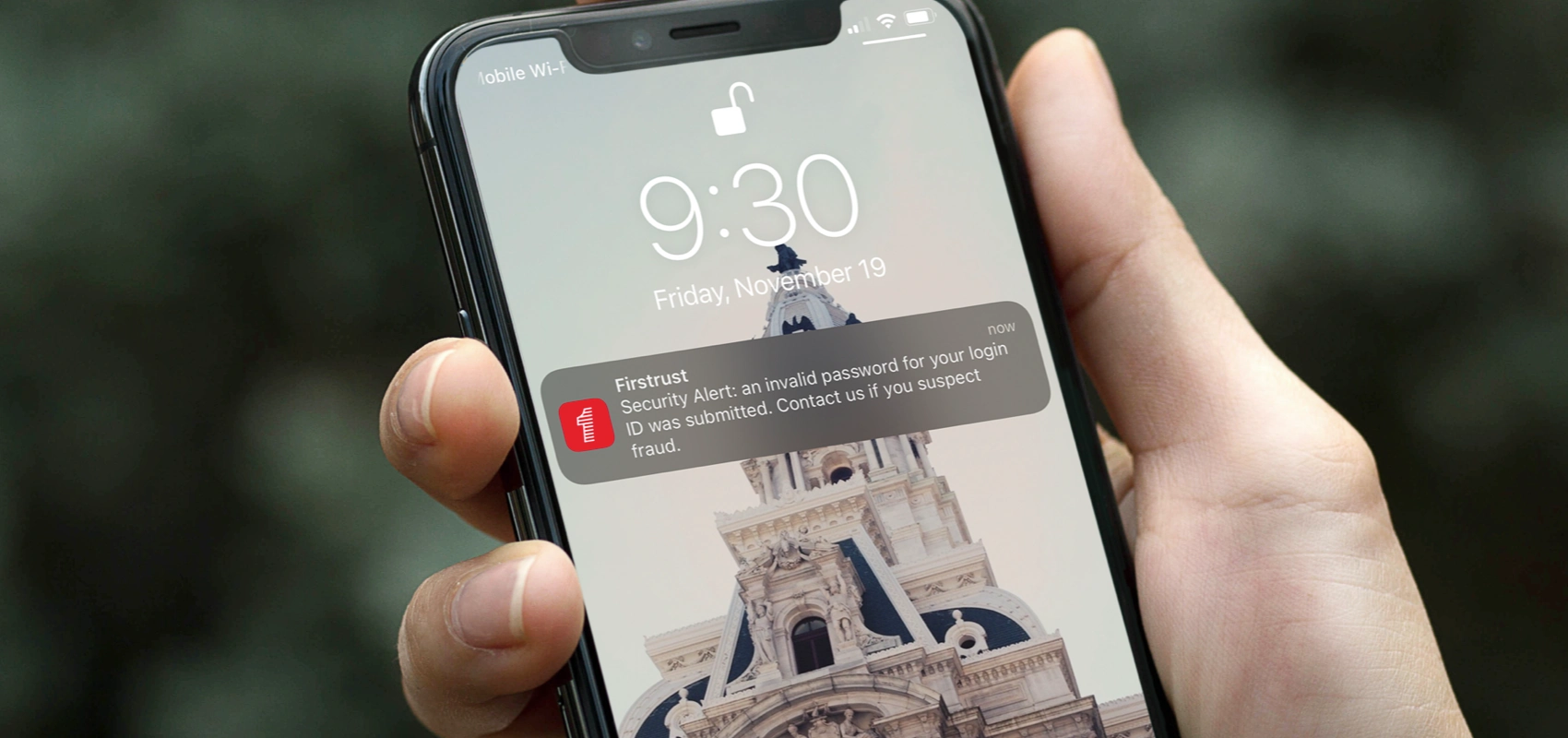 iPhone with a security alert on the lock screen from Firstrust Bank mobile app