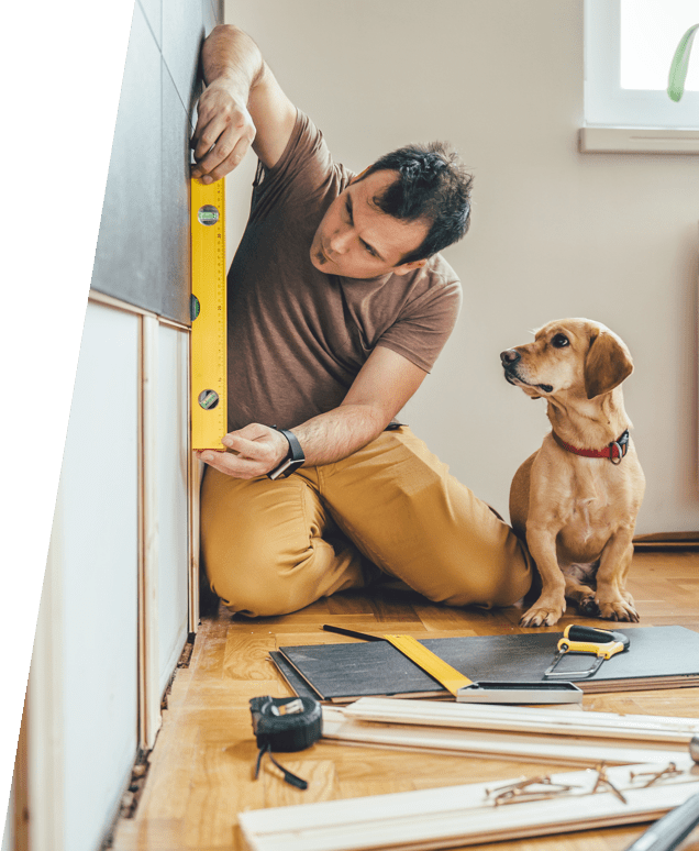 Homeowner measuring a wall with his dog sitting next to him