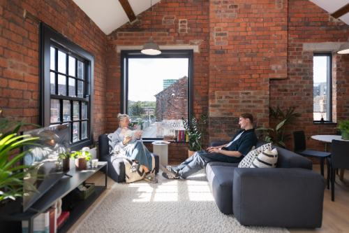 two friends sat in a living room with large window
