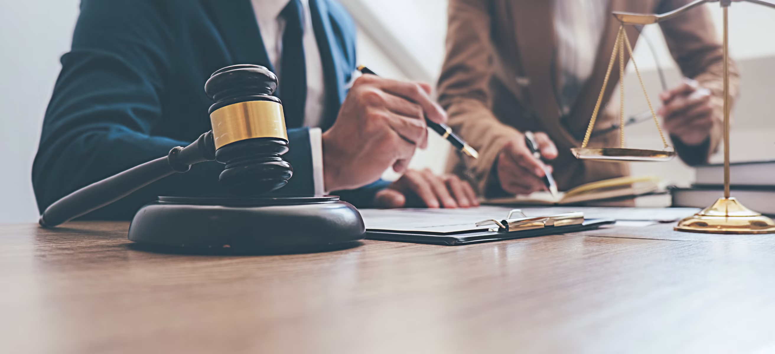 Dwóch profesjonalistów przeglądających dokumenty prawne przy biurku na pierwszym planie, symbolizującą zgodność z prawem i dyskusje na temat prywatności danych.