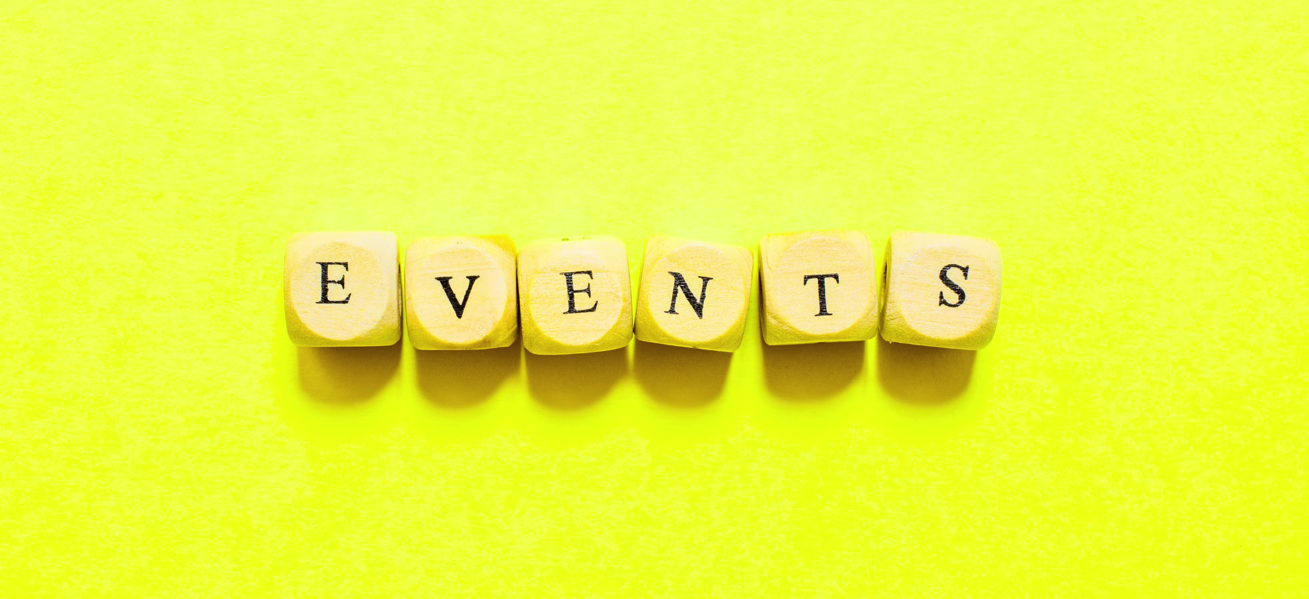 The word "events" formed with wooden blocks against a yellow backdrop, representing a guide for B2B event success.