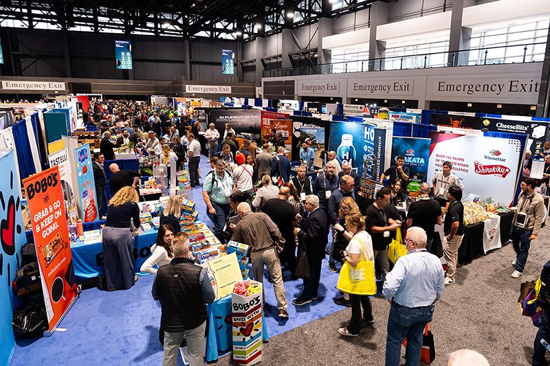 Attendees browsing product displays in a crowded section of the NACS exhibit hall.