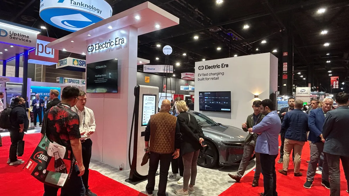 The Electric Era booth on the NACS show floor, with attendees gathered around a RetailEdge charging station and vehicle.