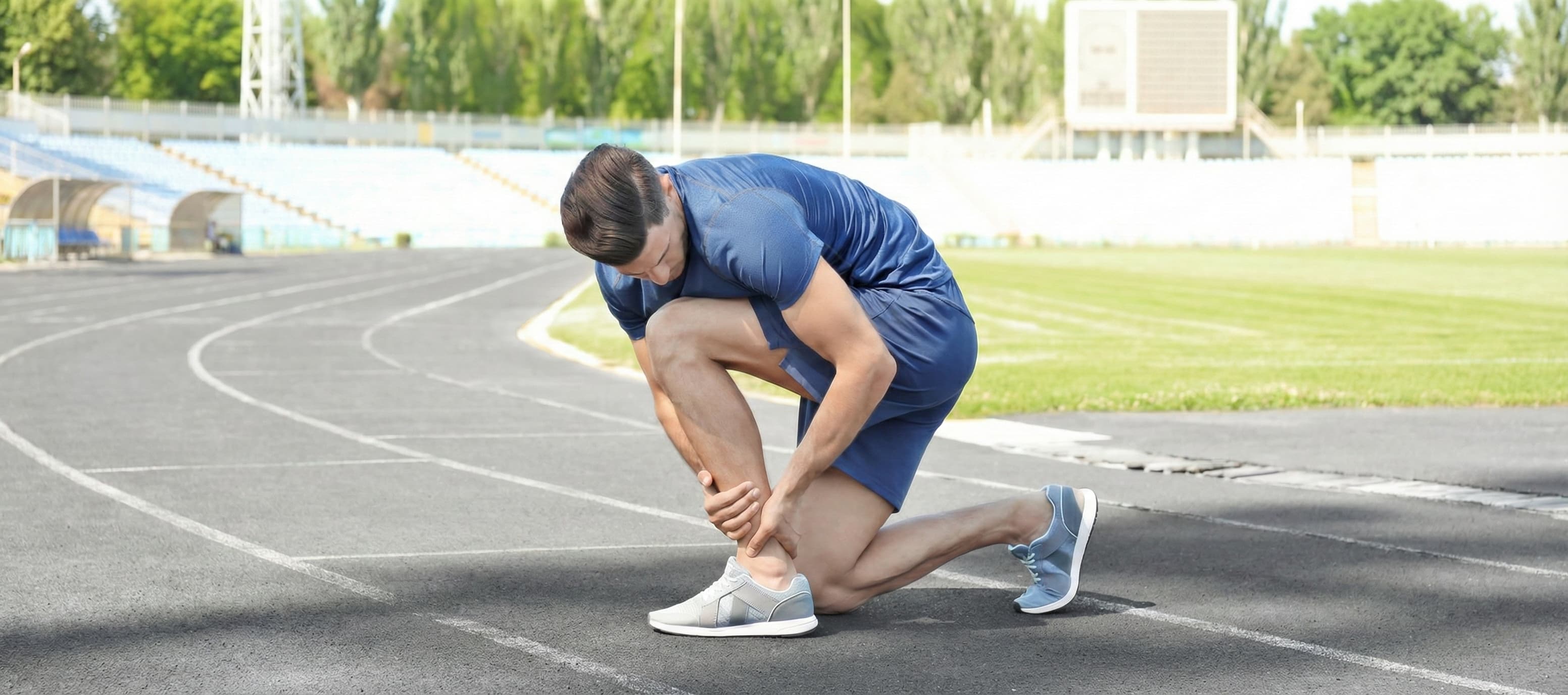 Athlete suffering from a calf muscle cramp on an athletics track