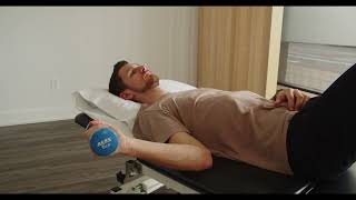 Physio démontrant mobilité de l'épaule en rotation externe avec poids