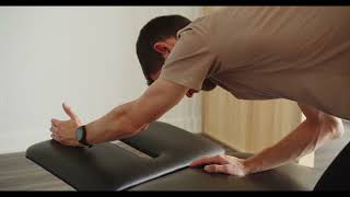 Physio démontrant mobilité de l'épaule en fin de flexion à genoux