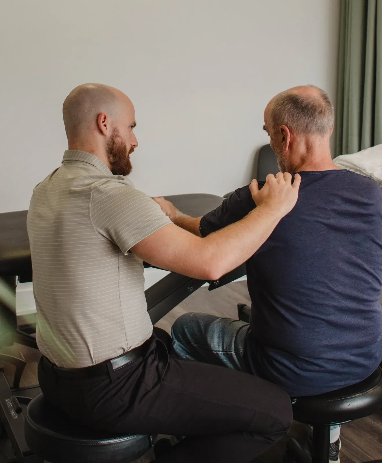 Physiothérapeute Physioactif évaluant l'épaule et le bras d'un patient assis en clinique de physiothérapie