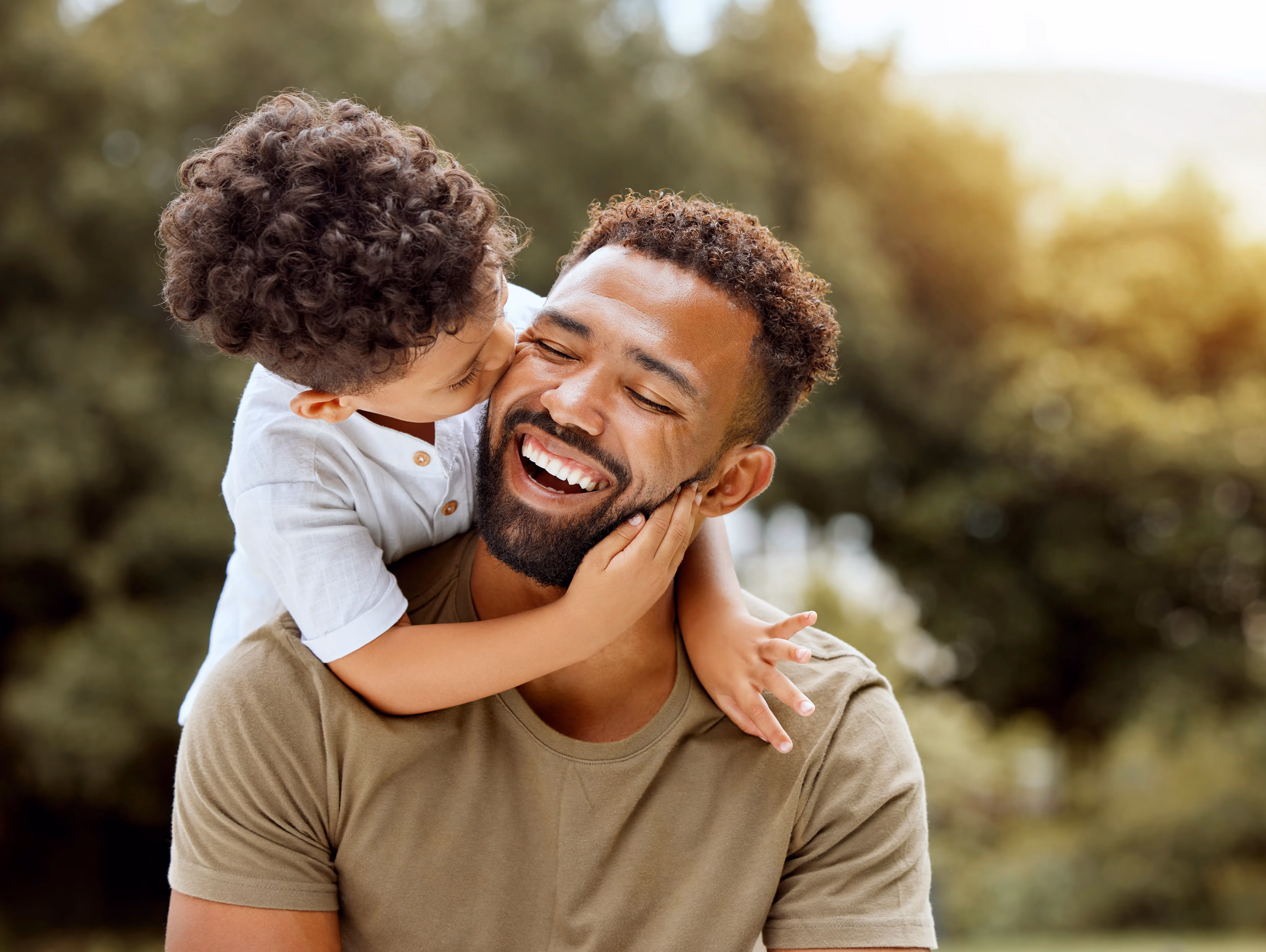 A father happily laughing as his child kisses him on the cheek, representing the family-friendly community at Avondale Commons in Avondale, AZ.