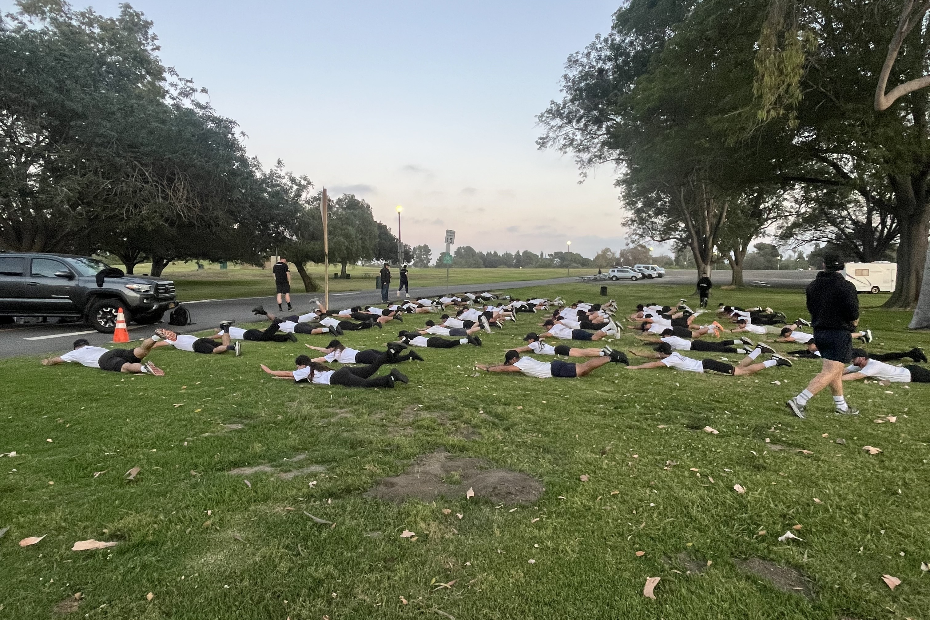 Large group of S2 recruits performing a plank drill outdoors at dawn