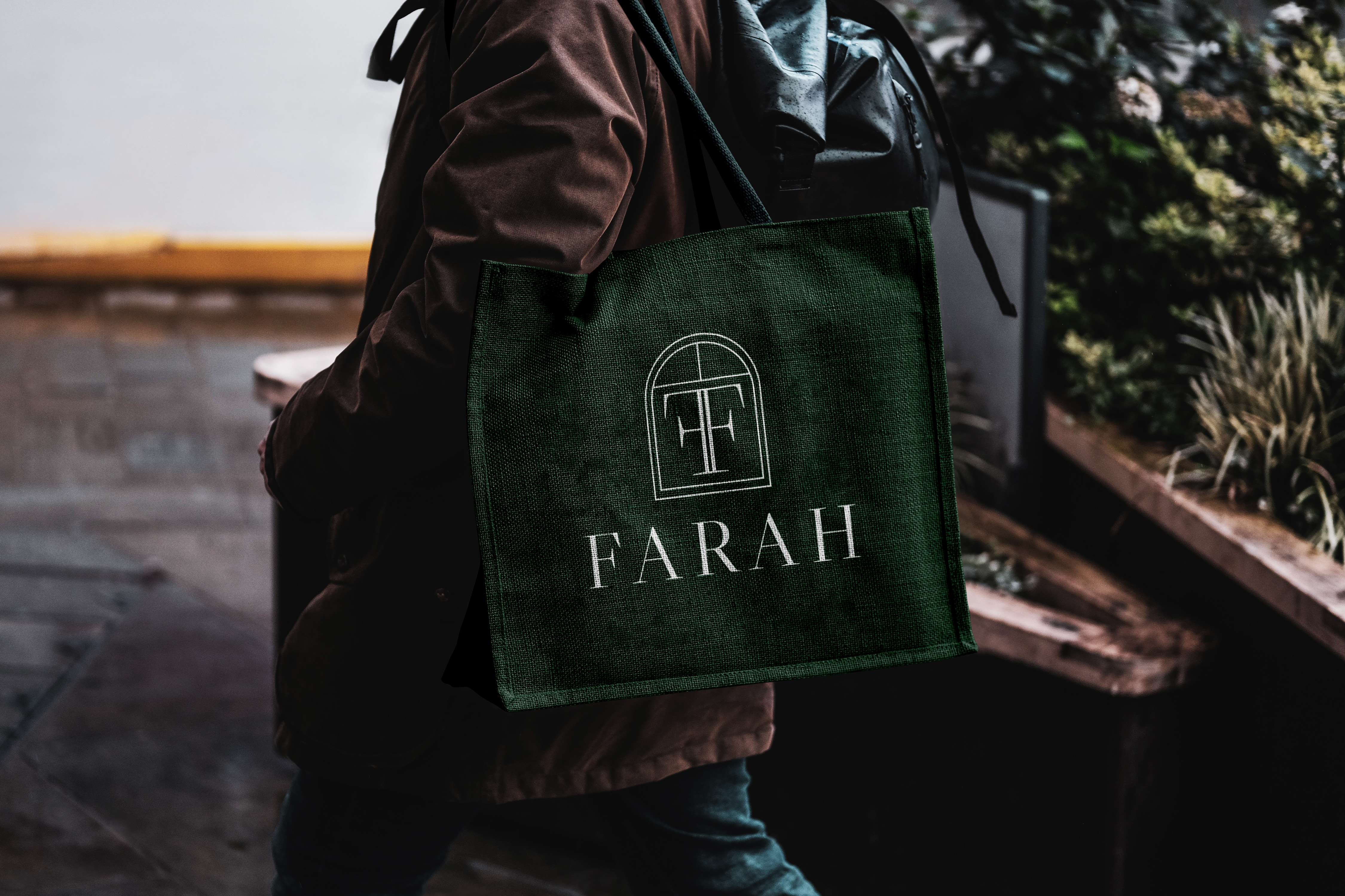 Person carrying a dark green tote bag with FARAH logo printed in white.