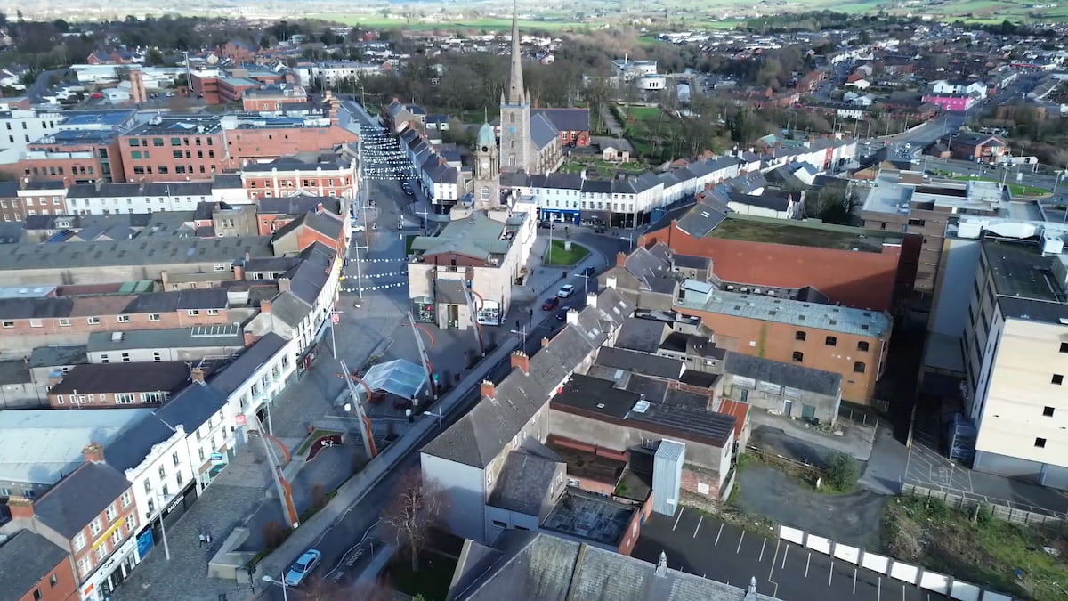 Wide view of Lisburn, capturing a blend of urban neighborhoods, commercial areas, and surrounding greenery.
