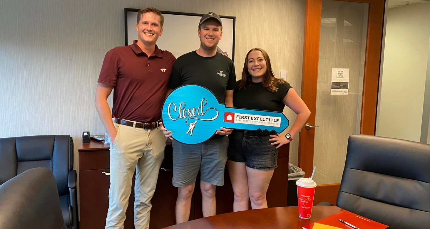 Photo of Jackson Brower with clients holding big blue key at closing table