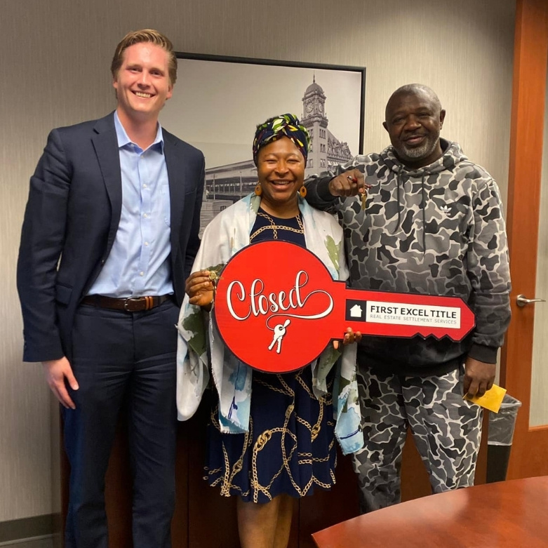 Photo of Jackson Brower with clients holding big red key at closing table