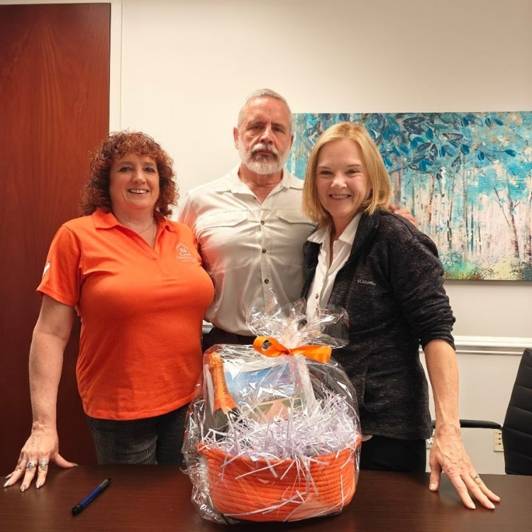 Janet Nowlin with clients at a closing standing behind a table with a gift basket