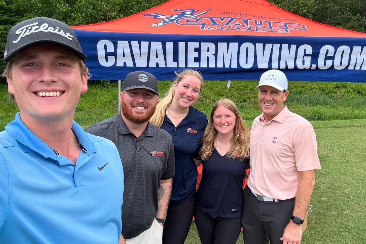 People standing in front of Cavalier Moving tent at golf course