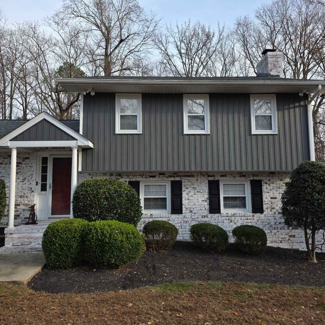 exterior of home with gray siding, white brick, and black shutters