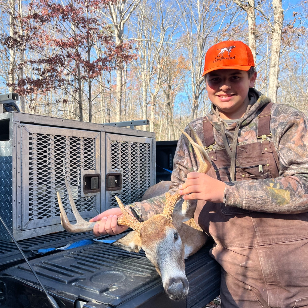 young hunter standing next to deer