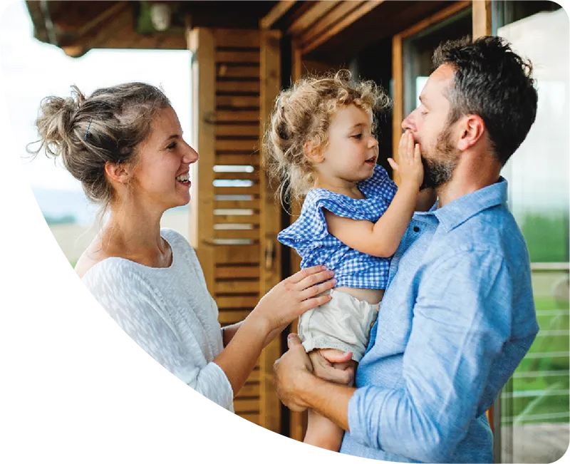 Mother and father holding daughter in front of house