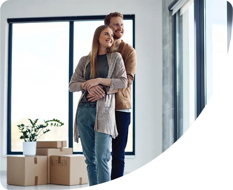 Man hugging women in new home with boxes around them