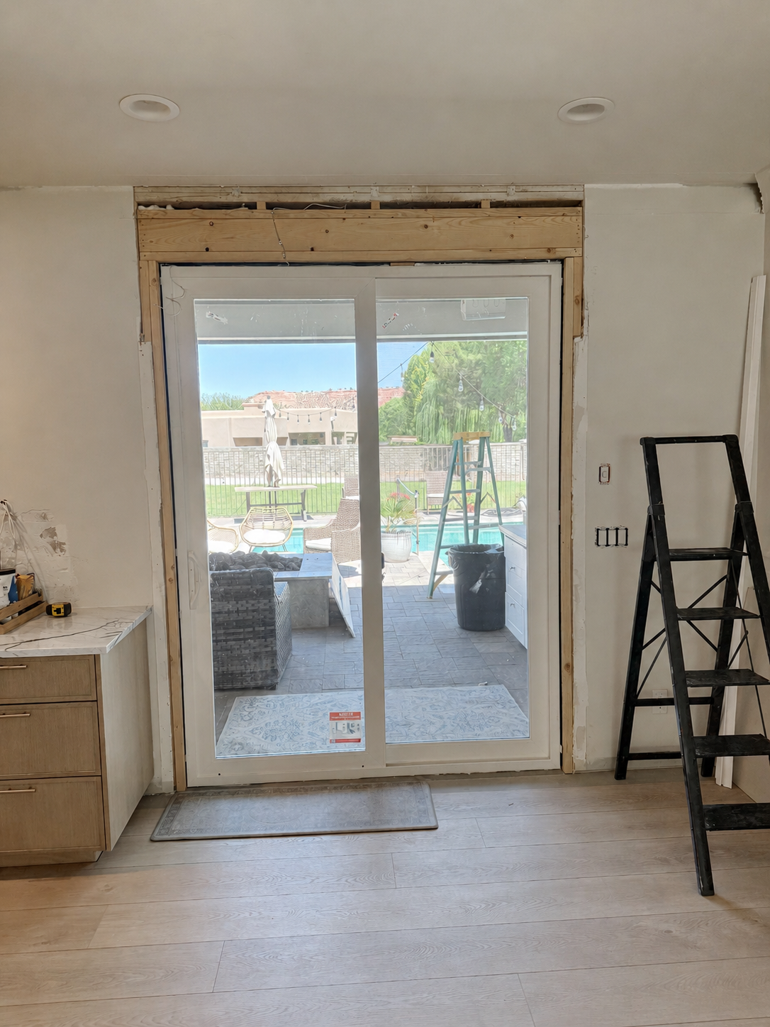 New 8-foot sliding glass door installed beneath the raised structural header before drywall finishing