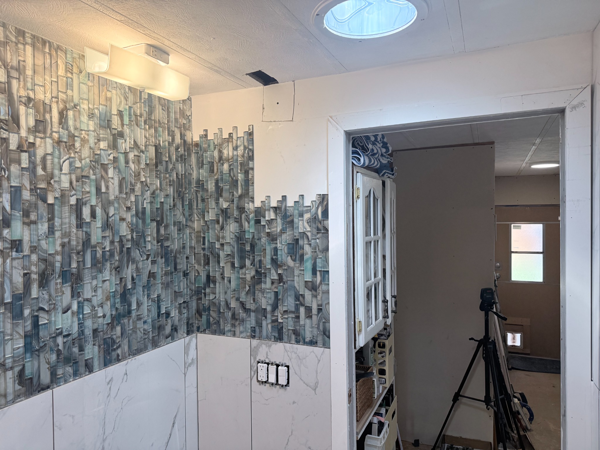 Glass mosaic tile accent installed across the adjacent bathroom wall