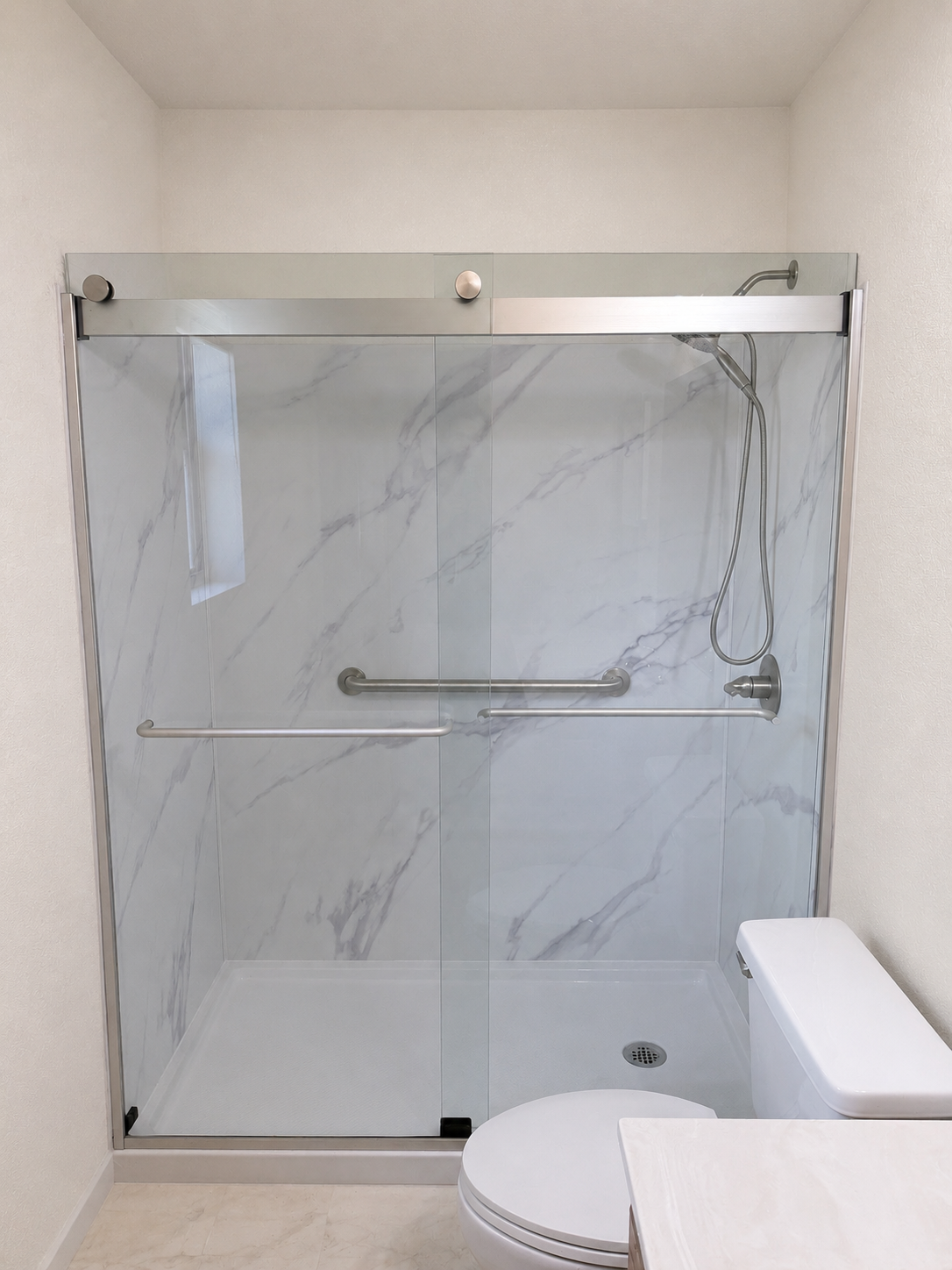 Finished walk-in shower with marble-look wall panels and sliding glass enclosure in Cottonwood, Arizona