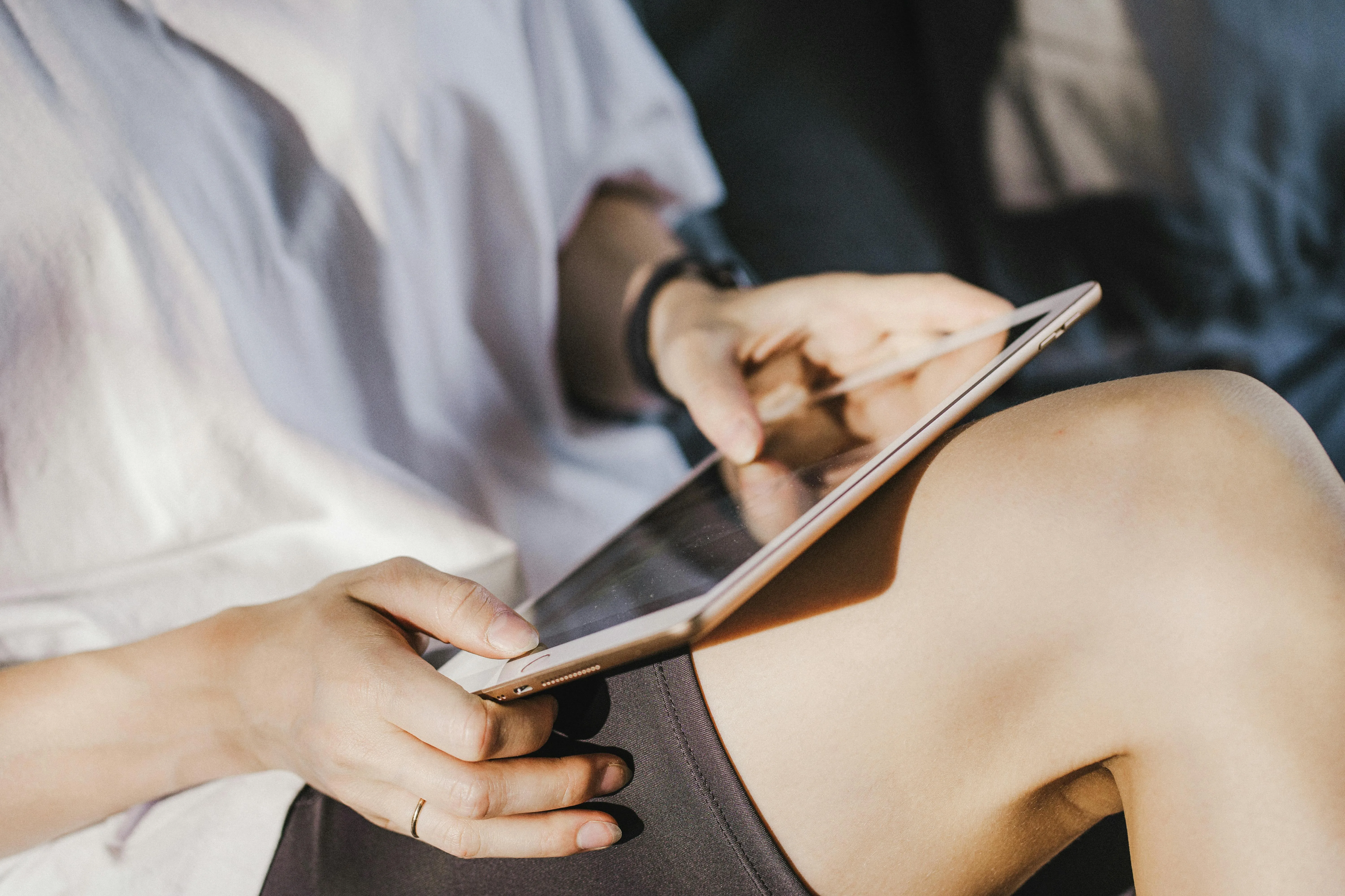 Person wearing shorts using a tablet resting on their knee in soft natural light.