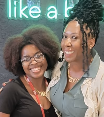 Boss Photo Wall: two property managers in BOSS necklaces at the Manage like a boss sign