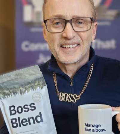 Boss Photo Wall: attendee in a BOSS necklace holding a bag of Boss Blend coffee and a Manage like a boss mug