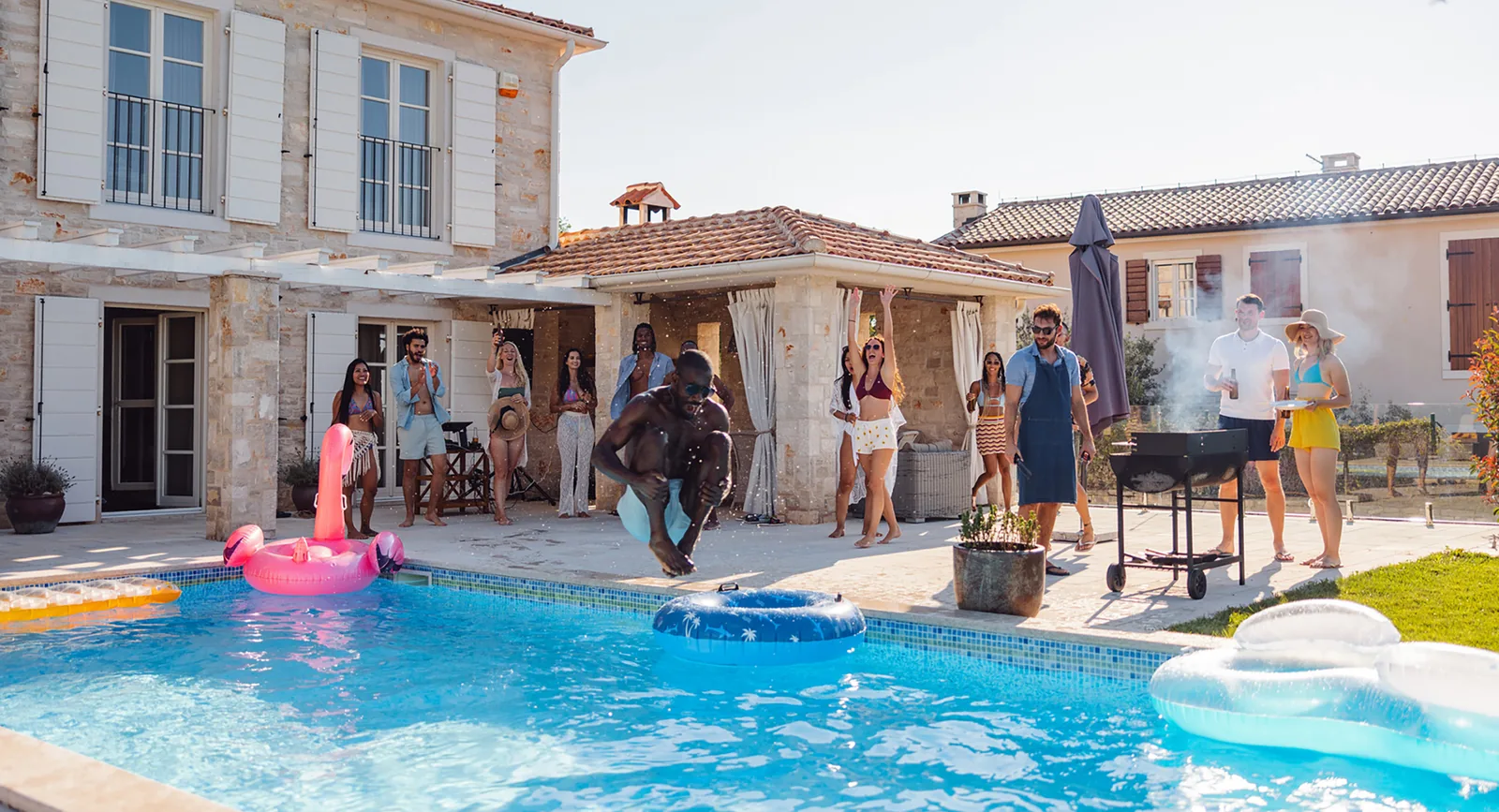 Residents enjoying a poolside party with a flamingo float and barbecue
