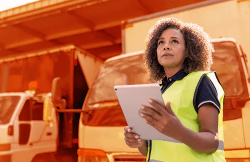 A woman in a yellow vest holding a tablet.