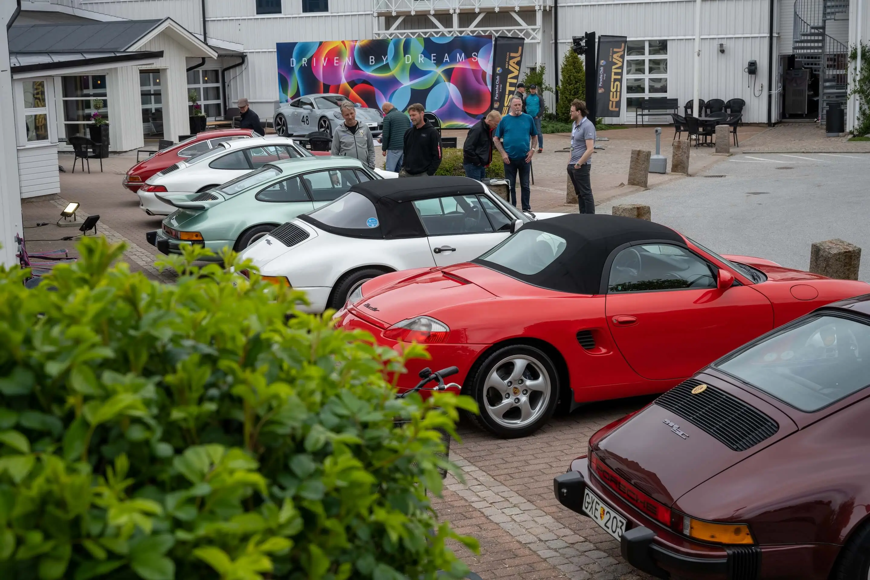 A Porsche meet-up in Norway with people walking among Porsche sports cars on display.