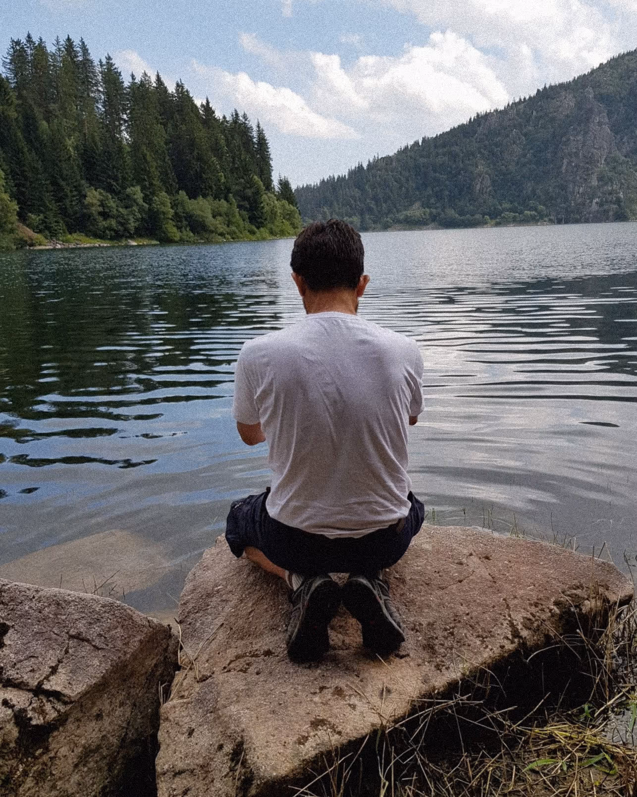 Homme de dos en posture de méditation devant un lac