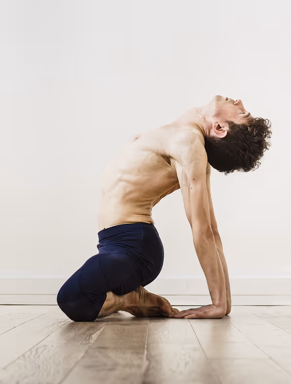 Antoine dans mulabandhasana, posture de yoga assise sur les pieds retournés