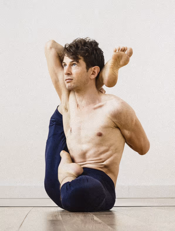 Antoine dans Viranchyasana B, posture de yoga en demi-lotus avec une jambe derrière la tête