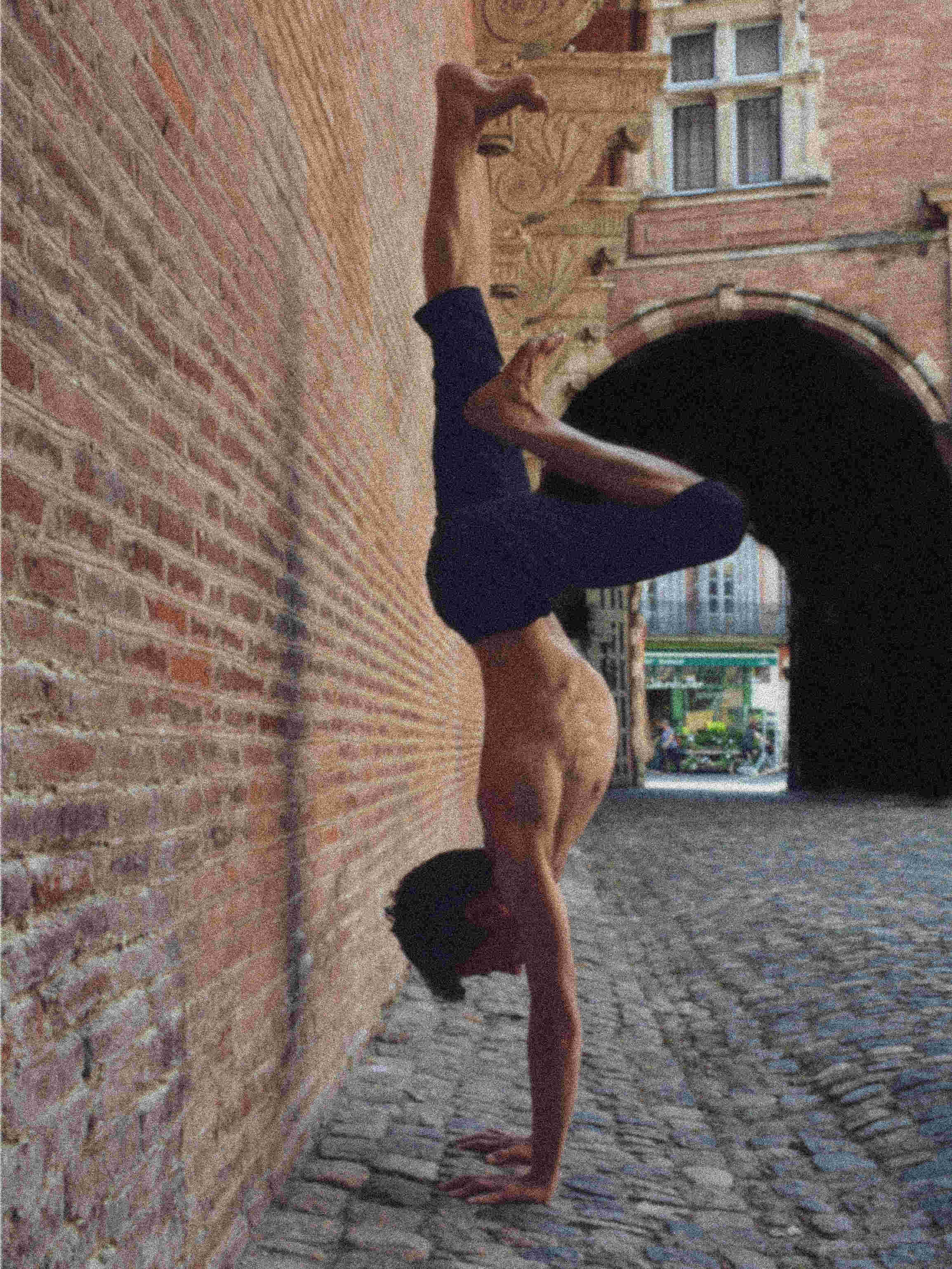 Antoine en équilibre sur les mains devant un mur en briques