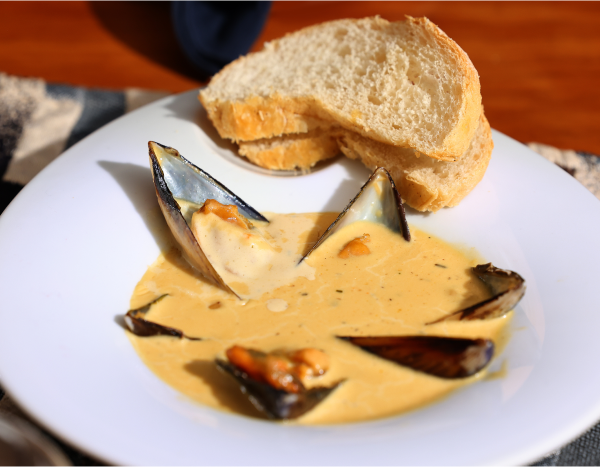 a plate of soup with mussels and bread