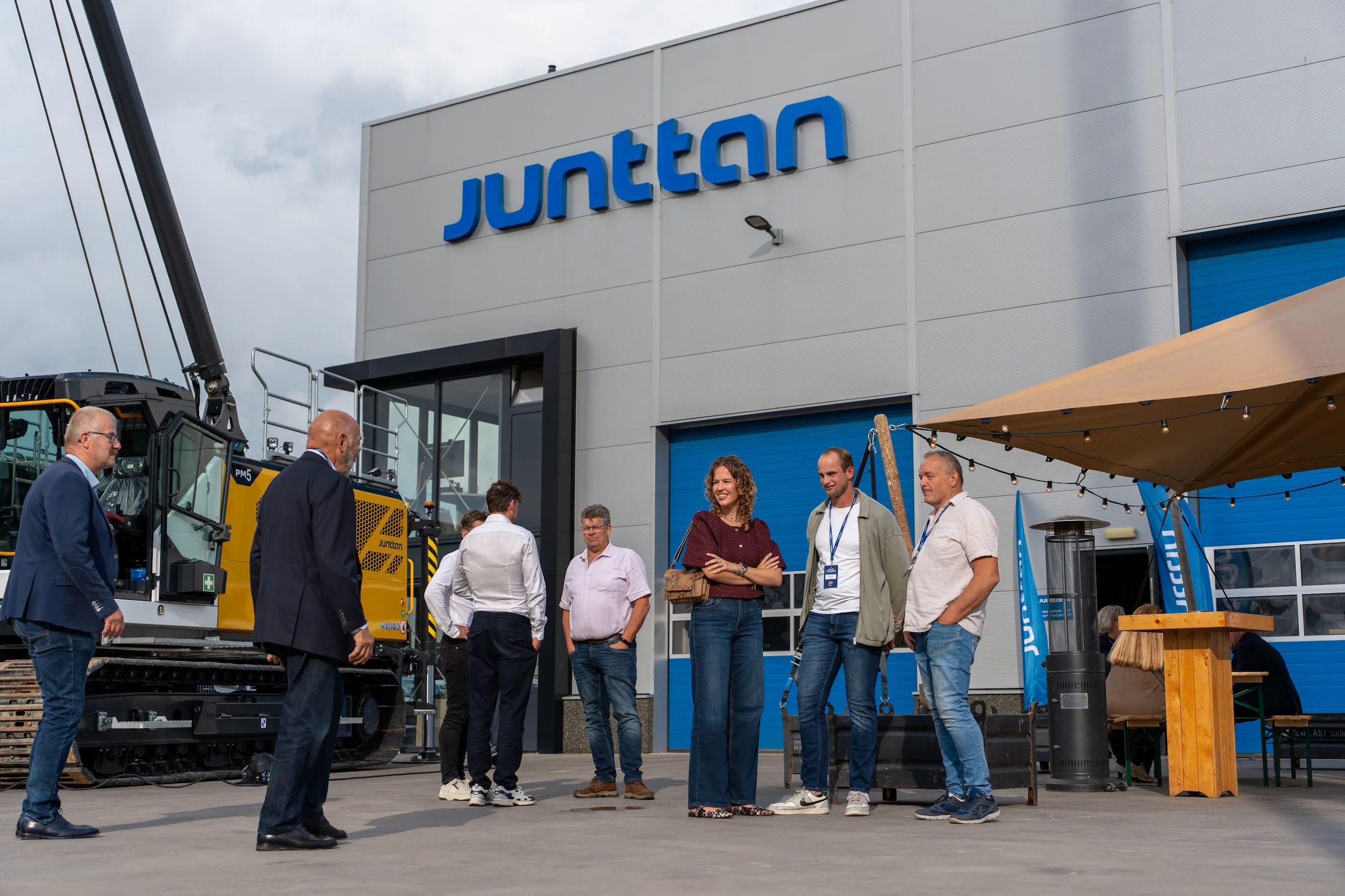 collega's en gasten praten buiten bij de nieuwe pm5-machine, in daglicht voor het pand
