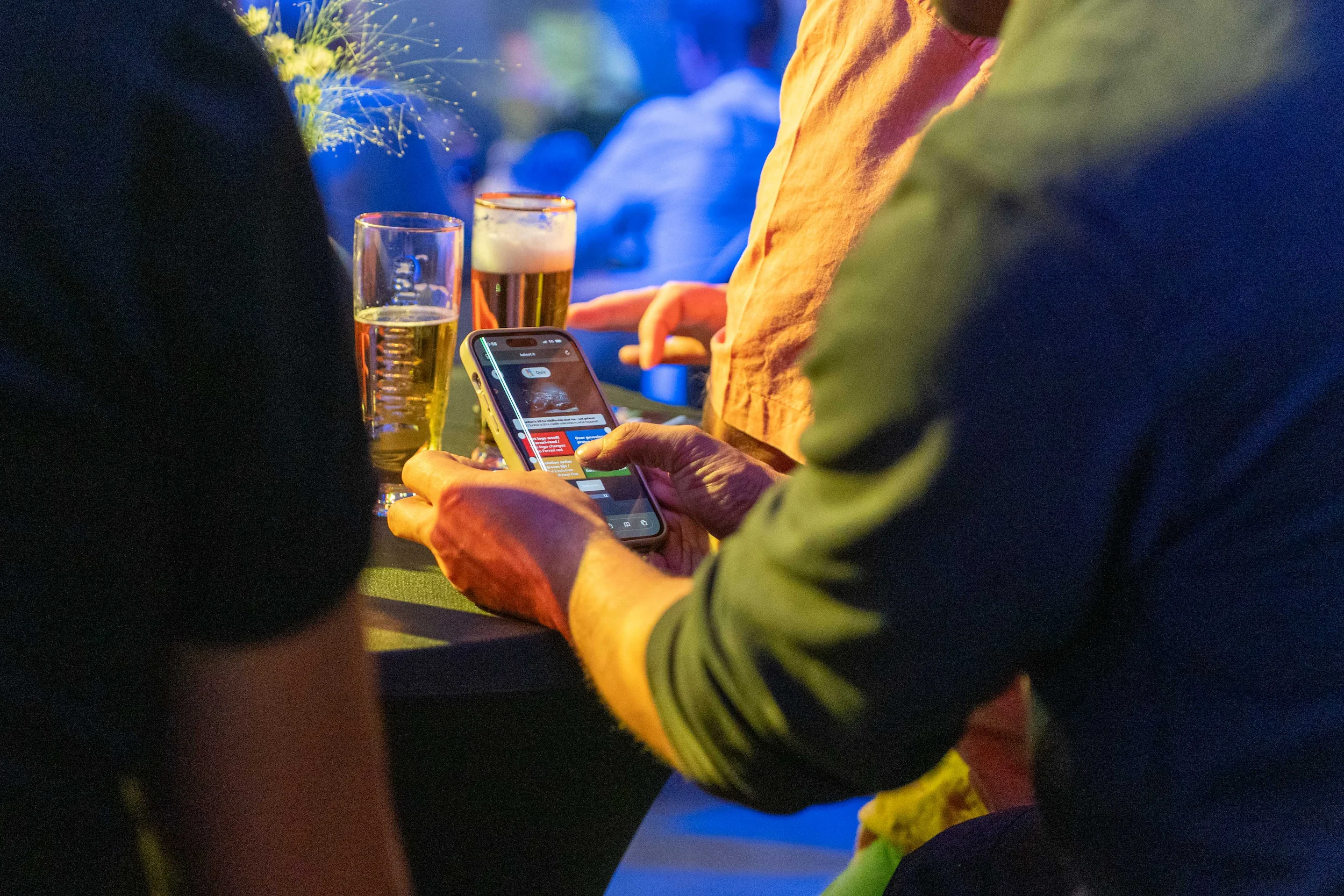 gasten aan de bar delen een quiz op de telefoon, biertjes binnen handbereik