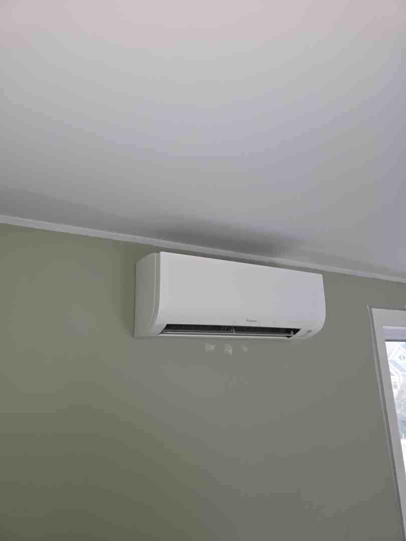 Homeowner adjusting a smart thermostat mounted on a modern living room wall - best heating setup for nova scotia weather