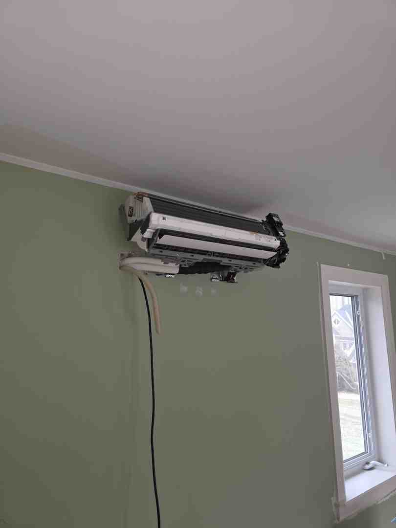 Homeowner checking a digital thermostat in a bright living room - spring hvac transition from heating to cooling Homeowner checking a digital thermostat in a bright living room - spring hvac transition from heating to cooling