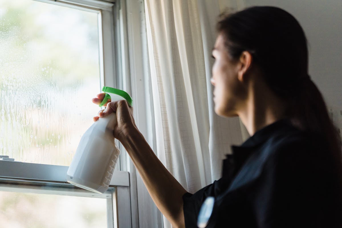 Housekeeper cleaning window as part of vacation rental turnover