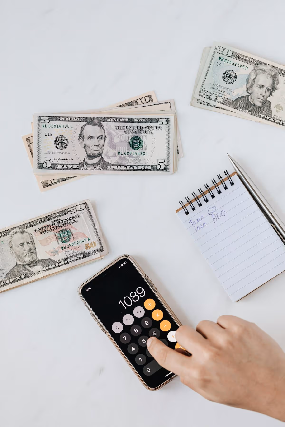 Person calculating profit on smartphone near banknotes