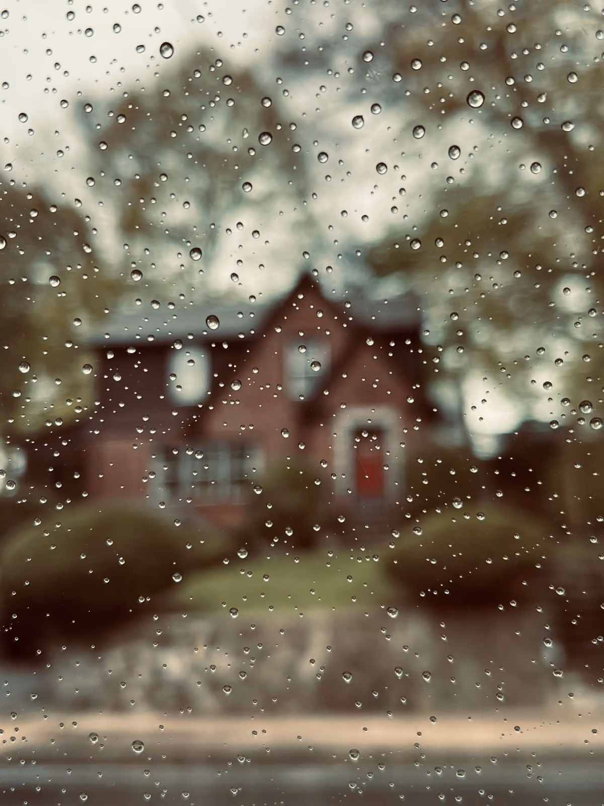 House seen through a rain-covered window during bad weather