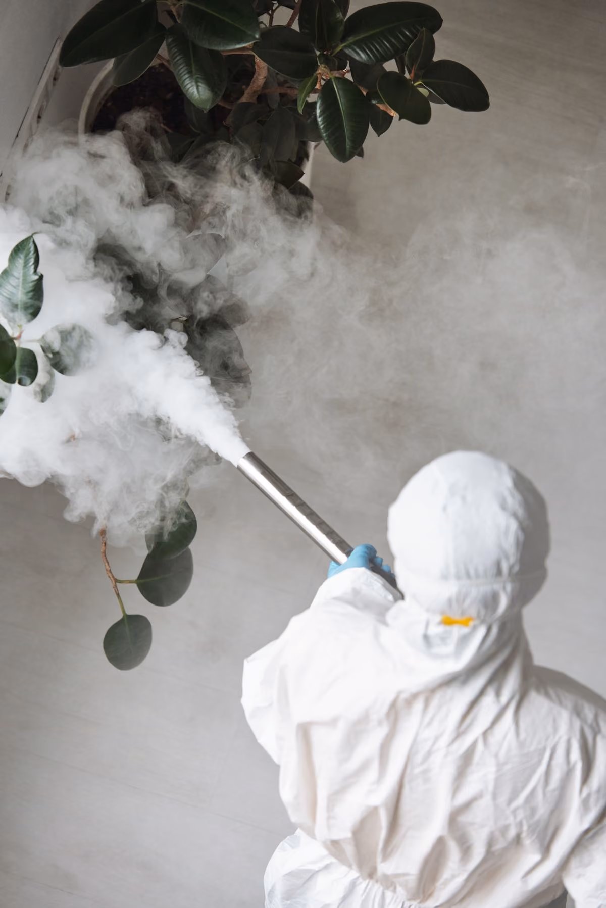 Pest control professional in protective gear treating an indoor space
