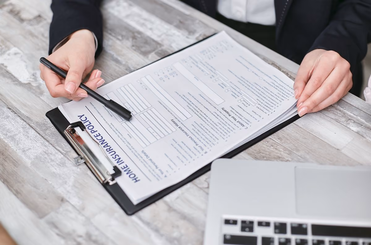 Mains examinant une police d'assurance habitation pour location courte durée