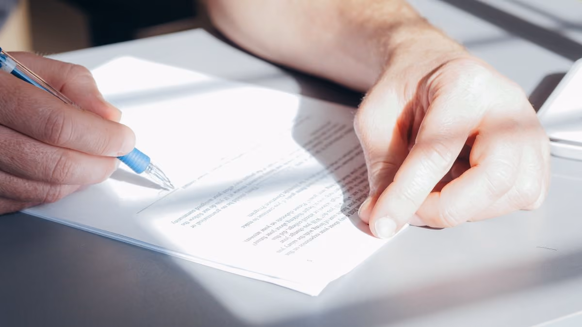 Hands signing a refund agreement with a pen