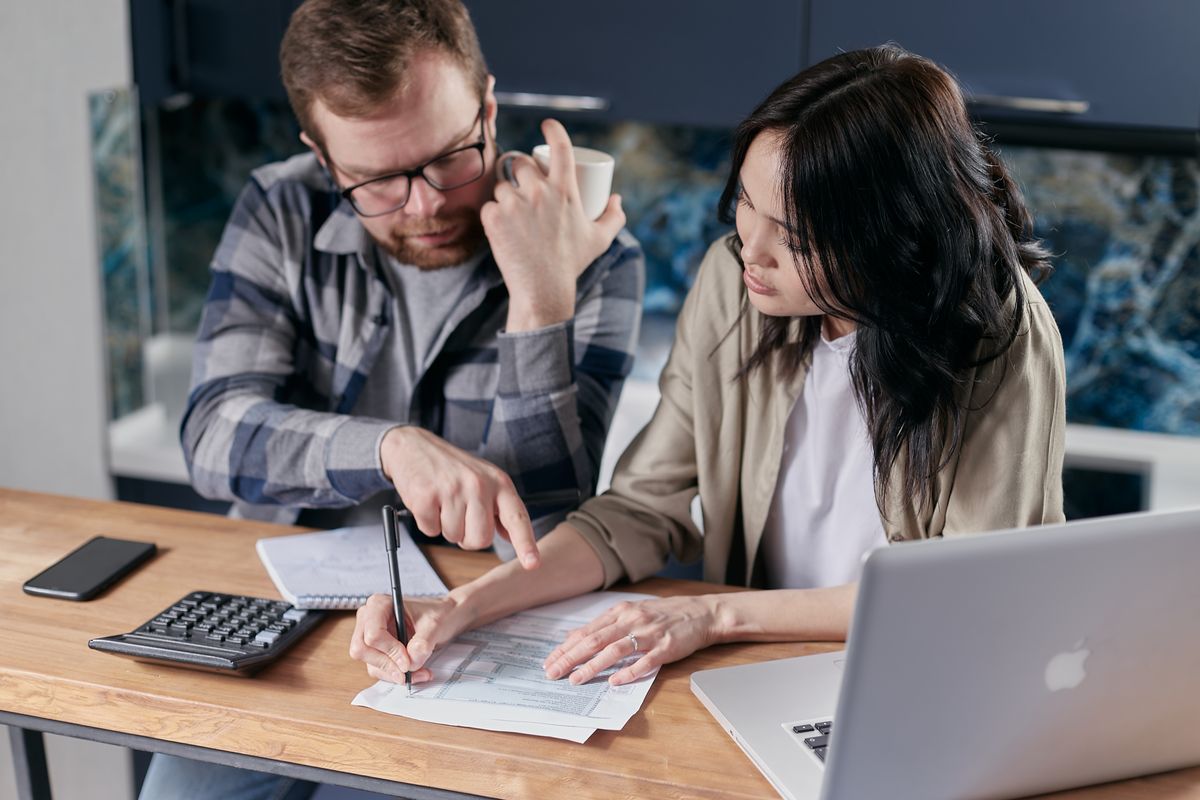 Couple examinant ses revenus locatifs avec une calculatrice et un ordinateur pour comparer micro-BIC et régime réel