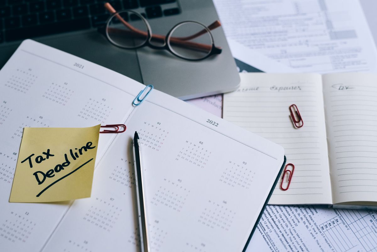Agenda avec un post-it Tax Deadline à côté de lunettes et d'un ordinateur portable